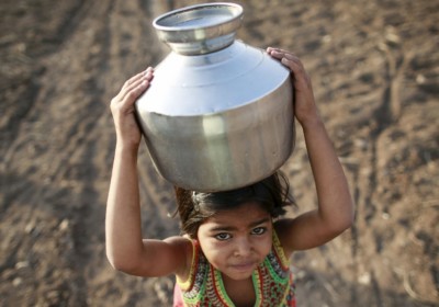 在烈日下，一位印度女孩頭頂滿載食水的鐵罐，走過 Latur 的田地，運水回家。（圖片來源：REUTERS）