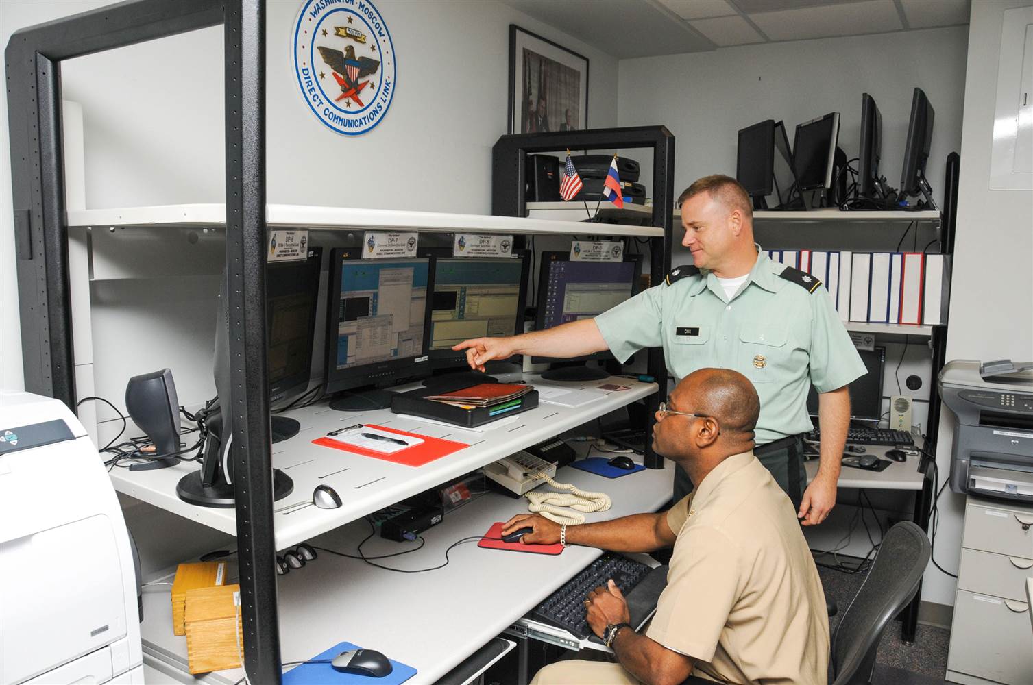 2013 年，美國海軍士官長 John E. Kelley（坐著）擔任總統通訊員，中校 Charles Cox 則為高級總統通訊員。美俄熱線最初使用的電傳打字機，已被電腦取代。 圖片來源：美國國防部
