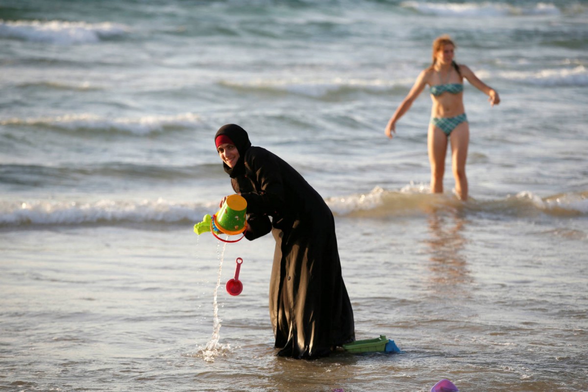 8 月 21 日，特拉維夫的沙灘上，一名穿著頭巾和罩袍的穆斯林女人正在嬉水。