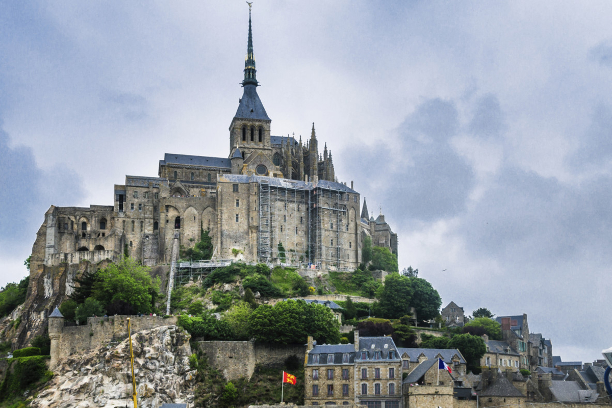 The historic Mont Saint-Michael cathedral rises majesticaly over the surrounding village off the coast of France.