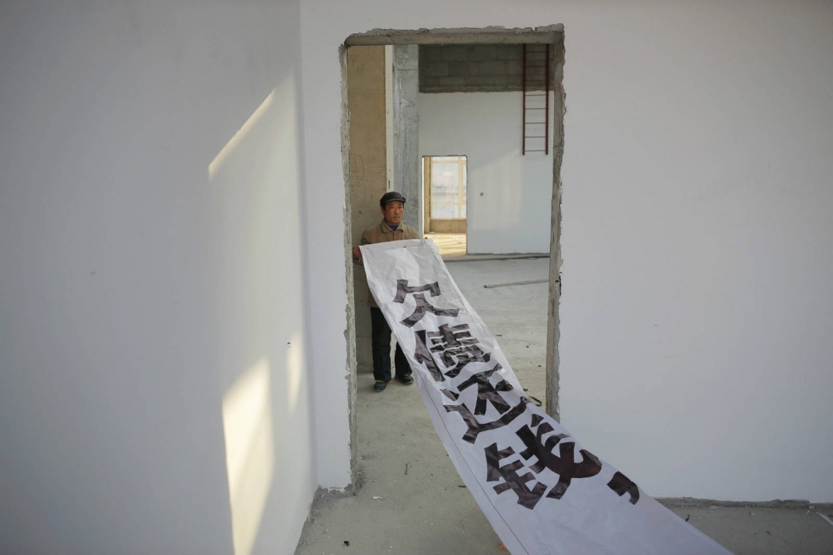 1 月 28 日，一個外省工人在河北省一棟未完工大樓展示「欠債還錢」橫額。