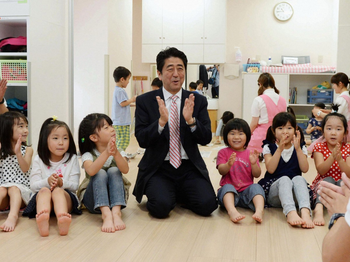 安倍探訪橫濱一間保育園時與幼兒打成一片，與此同時，超過 2 萬幼兒被排除在保育園外。　圖片來源：路透社