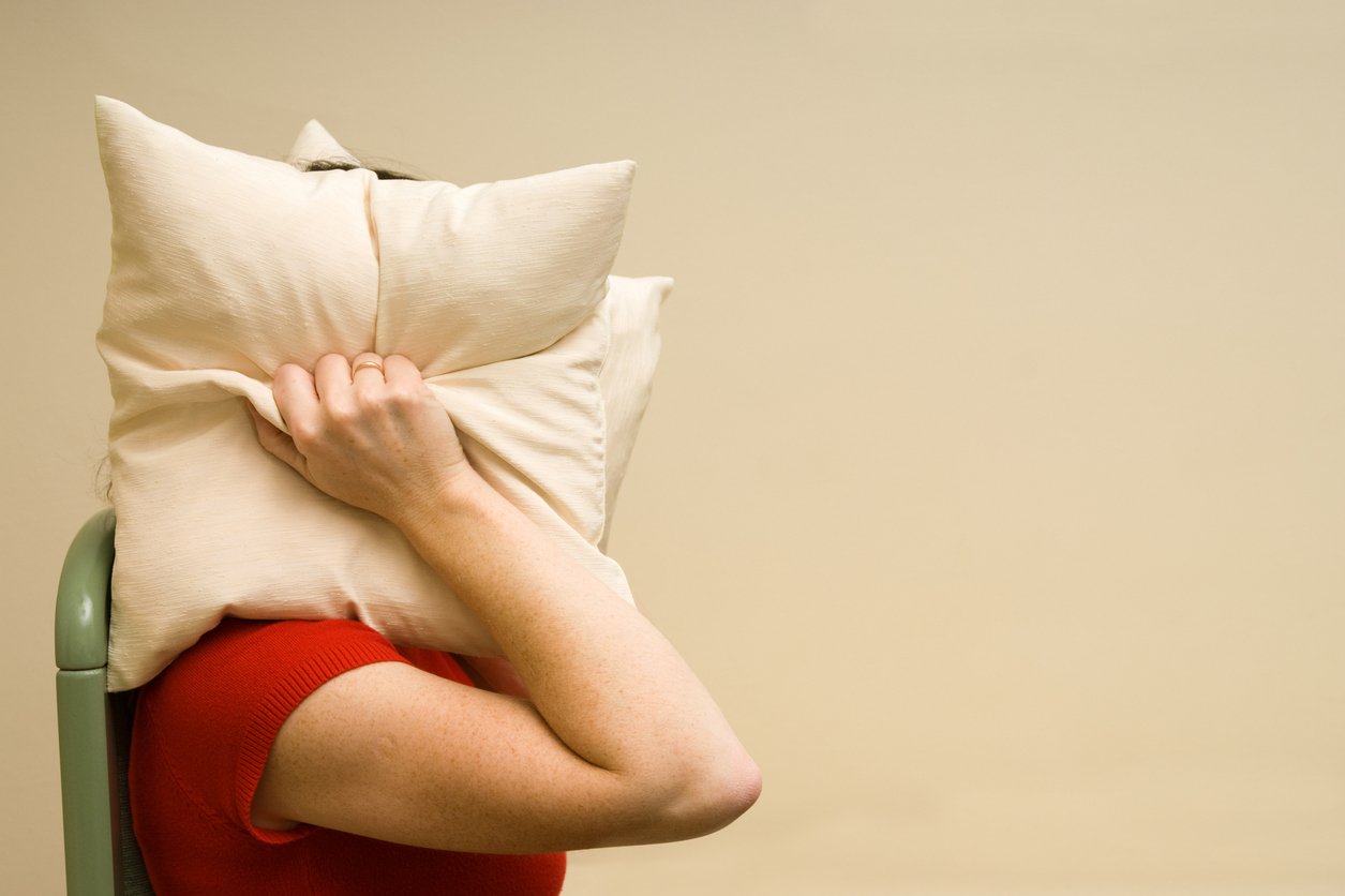 woman covering head with a pillow
