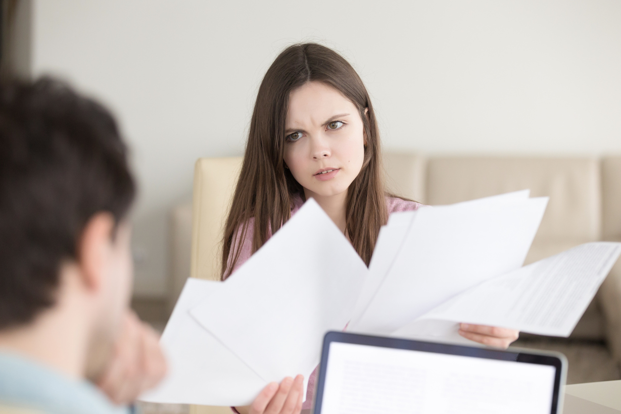 Serious confused woman holding papers, discussing documents with man